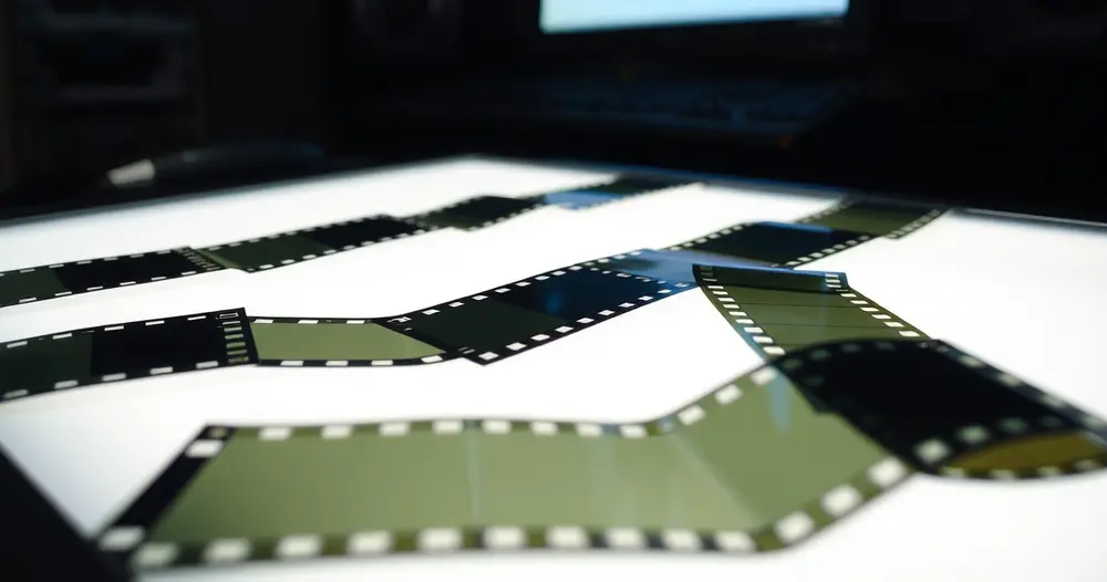 tiras de filme 35mm sobre mesa de luz em sala escura